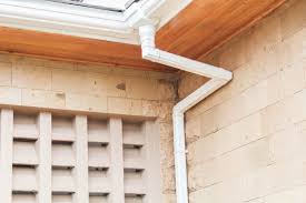 A metallic gutter on the edge of a roof with a downward extension