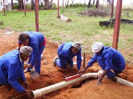 Four plumbers fixing underground pipes