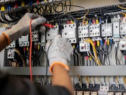 An electrician's hand working on a power panel