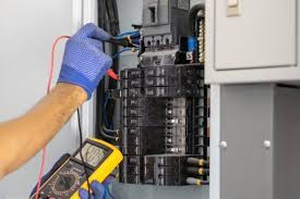 An electrician with a tester device testing power in a panel