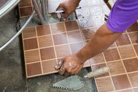 Hands on a man installing tiles on the floor