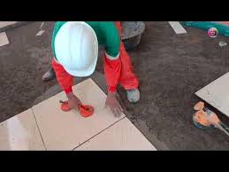 A man bent over aligning tiles on the floor