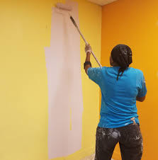 A female painter with a paint roller in hand painting