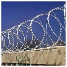 A razor wire roll installed on top of a wall fence