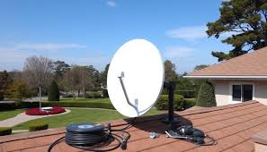 A satellite dish mounted on the top side of a house